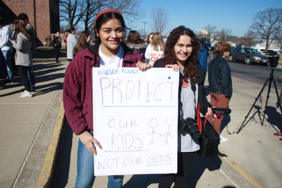 Seniors Juliana Custer and Silvia Aguila stand with a sign during the protest.