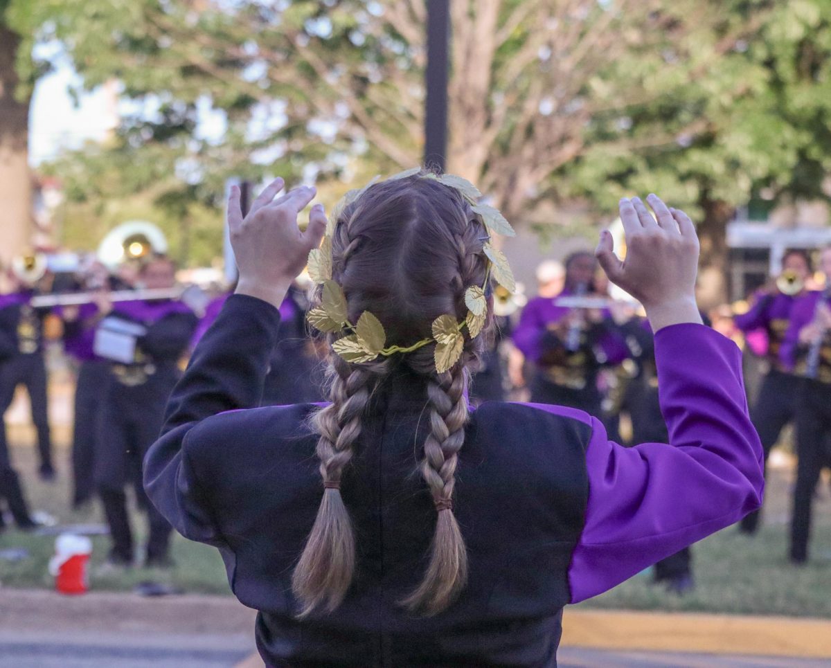 Senior drum major Mia Swope conducts the band as they warm up for the first football game of the year