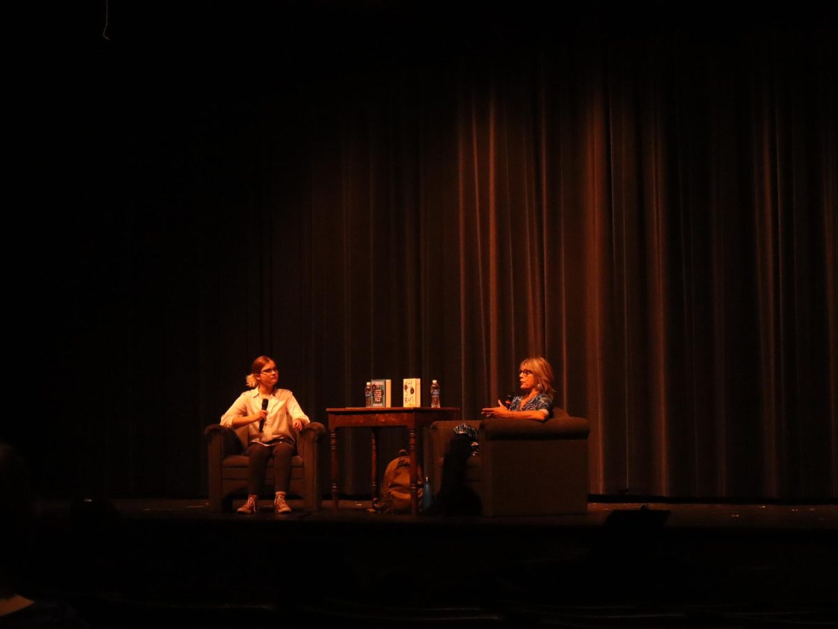 Senior Clarity Milarsky interviewing Slater in the auditorium. Students from all different grades sit below and listen to their conversation. 