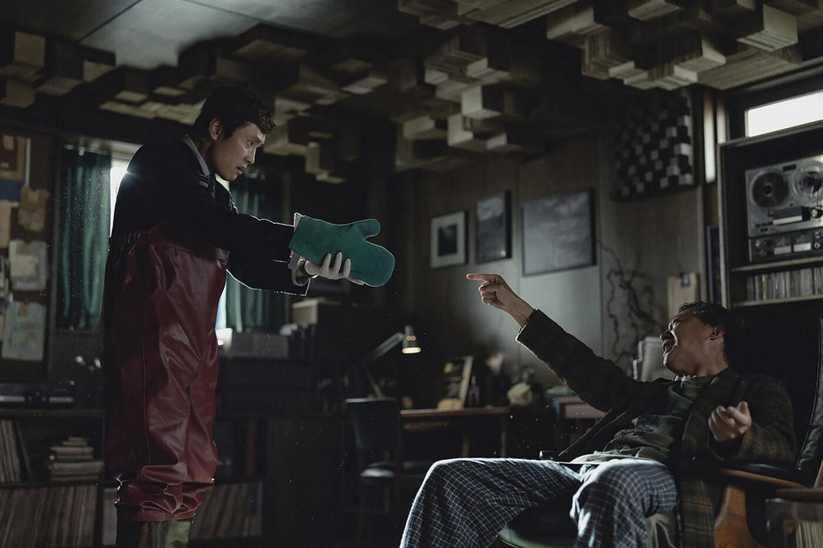 A still image from the movie No Other Choice. Depicts an interaction between the characters.
